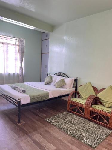 a bedroom with a large bed and two chairs at Cozy Haven 1018 Homestay in Shillong