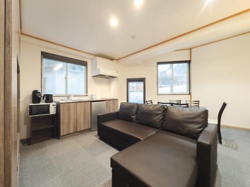 a living room with a couch and a kitchen at Schanze Nozawa in Nozawa Onsen