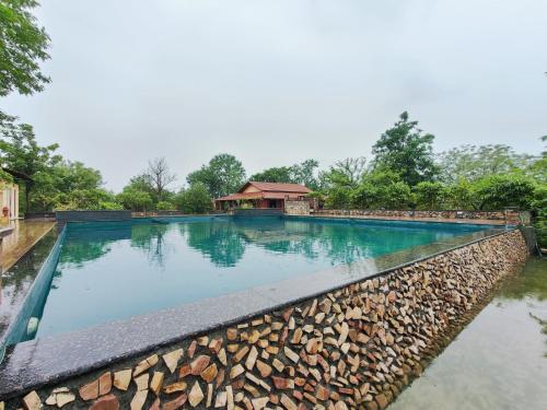 a swimming pool at a resort with a stone wall at Haveli Anirudh - Royalty Redefined in Jaipur