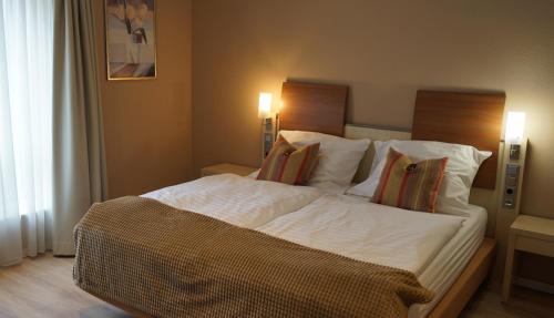 a bedroom with a large bed with white sheets and pillows at Hotel Restaurant Strümper Hof in Meerbusch