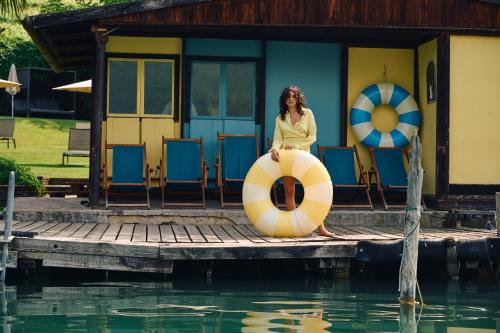 a woman sitting on a raft on a dock next to a house at Leuchtenburg am See in Caldaro