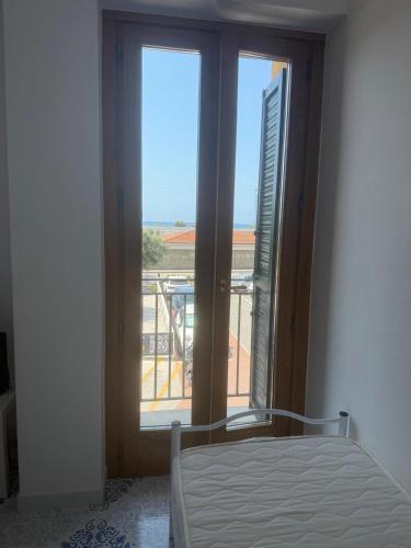 a bedroom with a window with a view of a balcony at Giorni fantastici - appartamenti fronte mare in Marina di Ascea