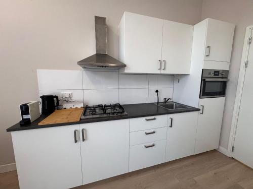 a kitchen with white cabinets and a stove top oven at Getferweg 50-2 City Appartement in Enschede
