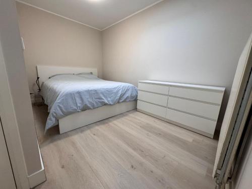 ein weißes Schlafzimmer mit einem Bett und Holzboden in der Unterkunft Getferweg 50-2 City Appartement in Enschede