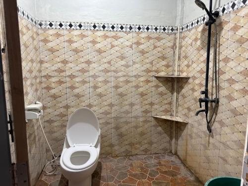 a bathroom with a toilet and a tiled wall at Sumbawa Maluk Homestay Kost tika in Maluk