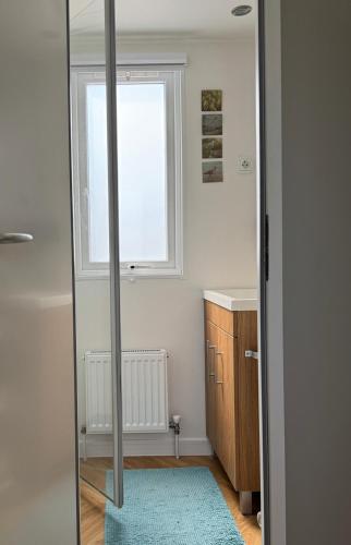 a bathroom with a mirror and a sink and a window at Chalet Oostkapelle in Oostkapelle