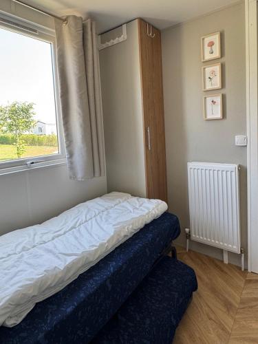a bed in a room with a window and a blue mattress at Chalet Oostkapelle in Oostkapelle
