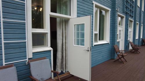 a blue house with a white door and chairs at Lapin Satu in Posio