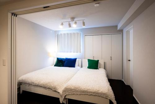 a bedroom with a bed with blue and green pillows at エルモス唐人102 in Muromimachi