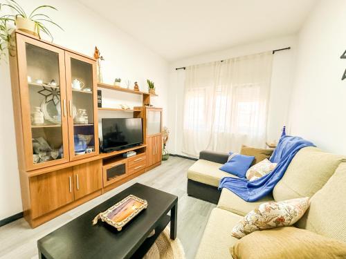 a living room with a couch and a tv at Apartamento Susurros do Atlántico by ALÔGA in Fisterra