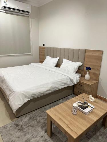 - une chambre avec un grand lit et une table en bois dans l'établissement شقق رحابة المكان للشقق المفروشه, à Al Kharj