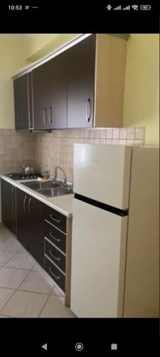 a kitchen with a white refrigerator and a sink at Nitro Inn Orikum - SEA and GARDEN in Orikum