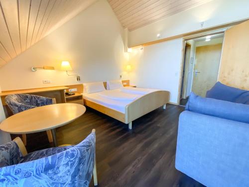 a hotel room with a bed and a table and chairs at Berggasthof Höchsten in Illmensee