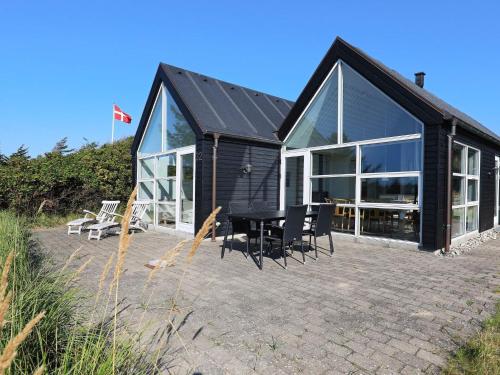 a black house with chairs and a table on a patio at 5 star holiday home in Blokhus in Blokhus