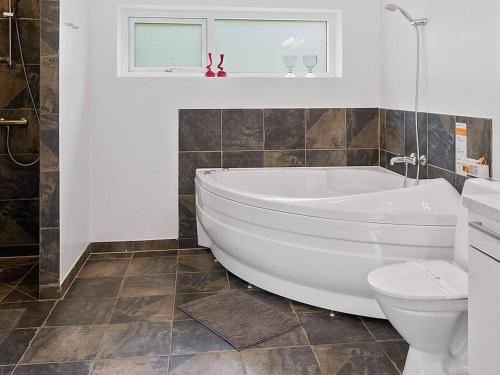 a bathroom with a white tub and a toilet at 5 star holiday home in Blokhus in Blokhus