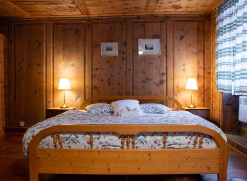 a bedroom with a bed with wooden walls and two lamps at Hotel Corona in Vicosoprano