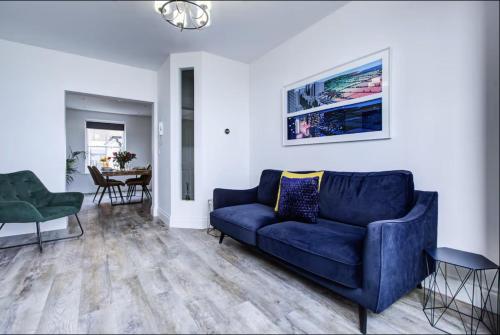 a living room with a blue couch and a table at Luxury 2 Bed Apartment with Stunning Sea View Steps from Old Town and Dreamland in Margate