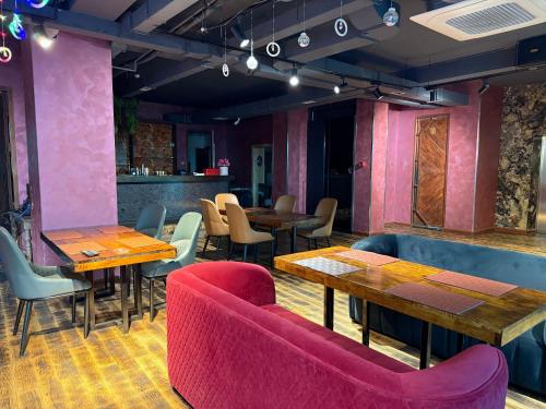 a restaurant with pink walls and wooden tables and chairs at Unity Hotel - Ulaanbaatar Railway Station in Ulaanbaatar