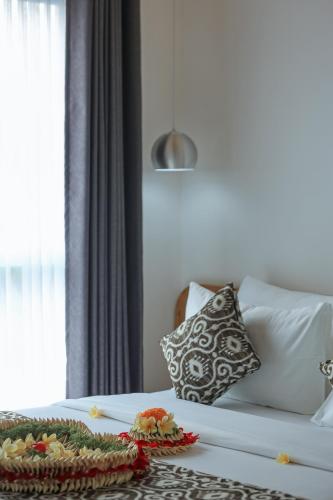 a bed with a pillow and a tray of food on it at Opin Villa Nusa Dua in Nusa Dua