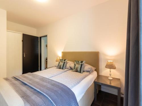 Un dormitorio con una cama y una mesa con una lámpara. en Holiday Flat Zugspitze Arena Ski Slopes, en Bichlbach