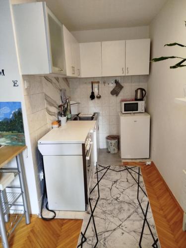 a kitchen with white cabinets and a white refrigerator at Uživanje u Sarajevu in Sarajevo
