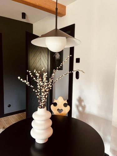 a black table with a white vase with flowers at Sleep & Sheep in Kościelisko