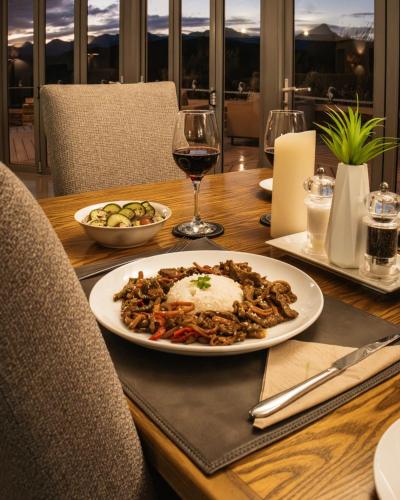 a table with a plate of food and a glass of wine at Landrani Farmstay in Oudtshoorn