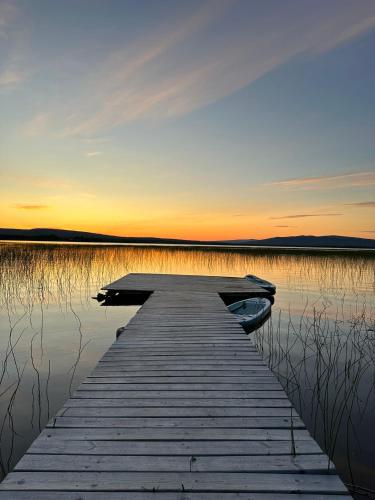 a dock on a lake with the sun setting at Camp Caroli Villa Aurora in Jukkasjärvi