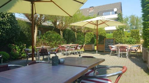 an outdoor patio with tables and chairs and umbrellas at Hotel Restaurant Strümper Hof in Meerbusch