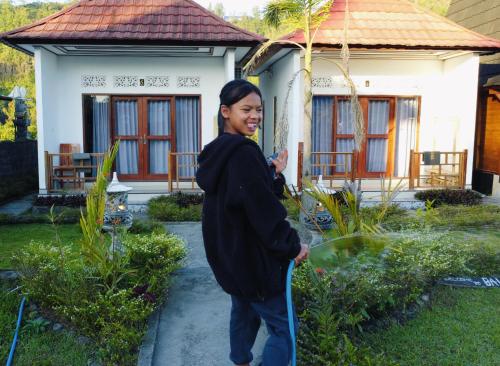 a woman standing in front of a house with a hose at Bali Cottages Lake View in Kintamani