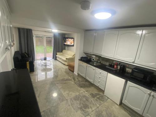 a kitchen with white cabinets and a couch in a room at THE HEATHROW LODGE LONDON Uk in Harmondsworth