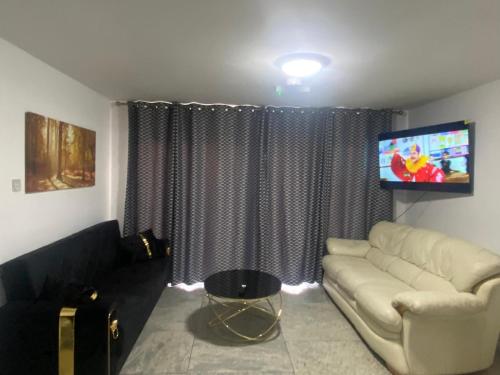 a living room with a couch and a flat screen tv at THE HEATHROW LODGE LONDON Uk in Harmondsworth