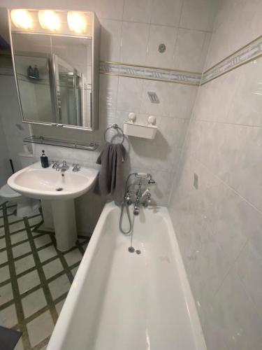 a bathroom with a bath tub and a sink at THE HEATHROW LODGE LONDON Uk in Harmondsworth
