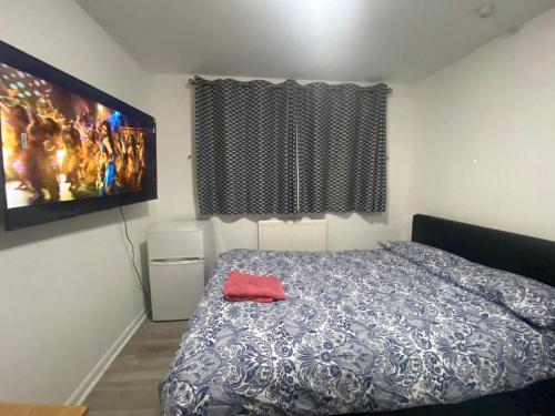 a bedroom with a bed and a tv on the wall at THE HEATHROW LODGE LONDON Uk in Harmondsworth