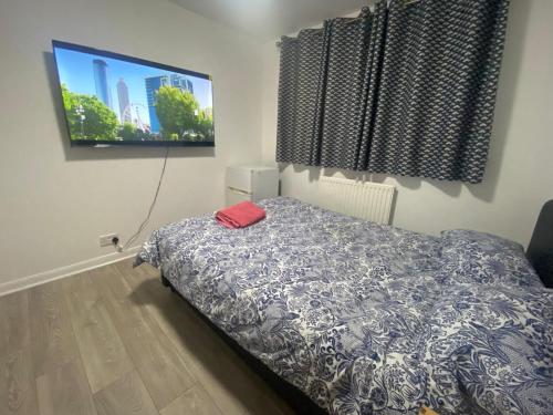 a bedroom with a bed and a flat screen tv at THE HEATHROW LODGE LONDON Uk in Harmondsworth