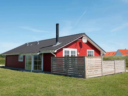 a red house with a fence in front of it at 8 person holiday home in Løkken-By Traum in Løkken