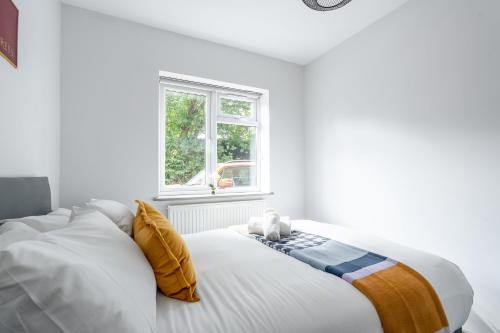 ein weißes Bett in einem weißen Zimmer mit Fenster in der Unterkunft 4Beds Contractor and Family Haven near Pinewood and Warner Bro studios in Chalfont Saint Peter