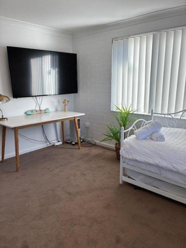 a bedroom with a desk and a bed and a table at Family Tides - Old Bar Holiday Rentals in Old Bar