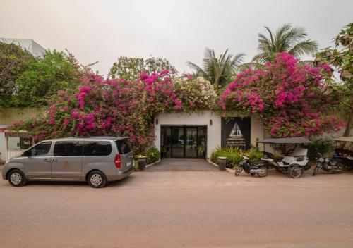 a van parked in front of a building with pink flowers at Angkor Land House in Phumĭ Réach Born
