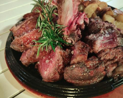 a plate of meat with a sprig of rosemary on it at Locanda di Bivigliano in Bivigliano