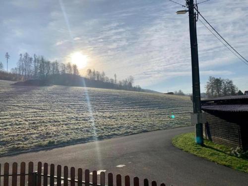 a sun shines on a field with a fence at Holiday Home in Zátor near Ještěd Ski Resort in Zátor