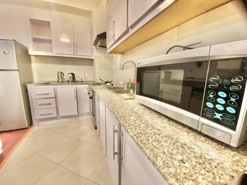 a kitchen with white cabinets and a microwave at Best Location & City Views Affordable Bole Stay in Addis Ababa