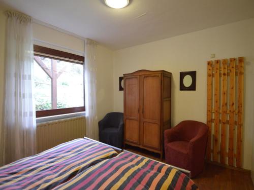 a bedroom with a bed and a cabinet and two chairs at Hellenthal Family Retreat in Hellenthal