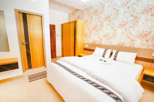 a bedroom with a large white bed in a room at Dubai Frame Residency And Hotel in Thottada