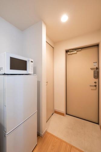 a room with a refrigerator and a door with a microwave at cocoloft Yoshizuka in Fukuoka