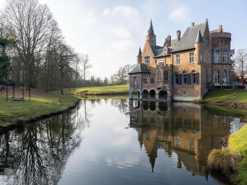 an old castle sitting on the side of a river at Apartment in Kruibeke Wissekerke Castle in Kruibeke
