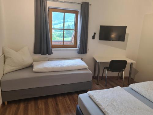 a room with a bed and a desk and a window at Ferienwohnung Schupfer - Free Parking, Seenähe & 5 Skigebieten in Aigen im Ennstal