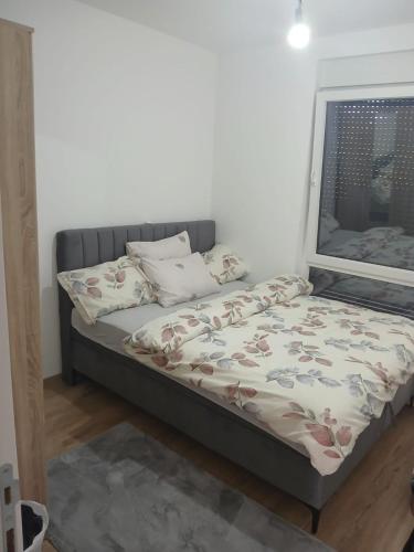 a bed sitting in a room with a window at Aprtman SALE in Vrnjačka Banja