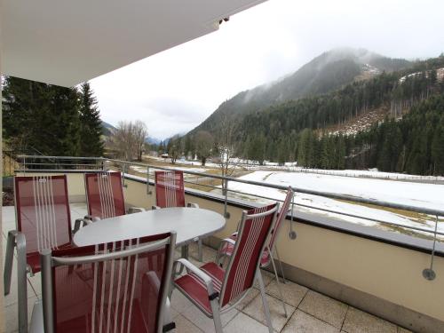 a table and chairs on a balcony with snow covered mountains at Chalet in Saalbach near Ski Lift in Saalbach Hinterglemm