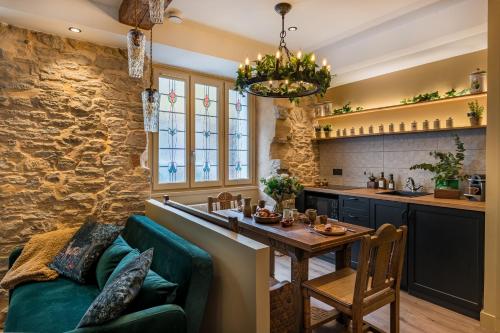 a kitchen and dining room with a green couch and a table at La Maison de l'Apothicaire - Un refuge enchanté avec balnéo en hyper-centre in Crémieu